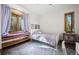 Bright bedroom featuring hardwood floors, a window seat, and lavender bedding with views of the surrounding forest at 6016 Stone Creek Dr, Evergreen, CO 80439