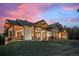 Beautifully landscaped home with outdoor seating area and stone accents under a vibrant sky at 6016 Stone Creek Dr, Evergreen, CO 80439