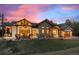 Stunning exterior featuring stone, timber accents, and outdoor seating under a vivid sunset sky at 6016 Stone Creek Dr, Evergreen, CO 80439