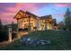 Rear exterior of a luxury home featuring expansive deck and patio with timber framing and stone accents at 6016 Stone Creek Dr, Evergreen, CO 80439