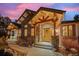 Inviting front entry featuring a beautiful wood door and natural stone accents under timber framing at 6016 Stone Creek Dr, Evergreen, CO 80439