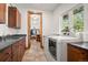 Bright laundry room features stone floors, wood cabinets, and an open doorway to a closet/dressing area at 6016 Stone Creek Dr, Evergreen, CO 80439