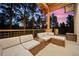 Covered patio with outdoor seating area featuring a sectional sofa and forest views at dusk at 6016 Stone Creek Dr, Evergreen, CO 80439