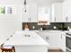 Well-lit kitchen showcasing white cabinetry, a quartz countertop island, and stainless steel appliances at 3955 W 13Th Ave, Denver, CO 80204