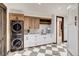 Bright laundry room featuring modern stacked washer/dryer and custom white and wood cabinetry at 2300 Boreas Pass Rd, Breckenridge, CO 80424
