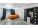 Cozy bedroom with gray wood floors, bright orange bedding and a black wardrobe for ample storage at 1261 Eagle St, Aurora, CO 80011