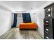 Bright bedroom with gray wood floors, bright orange bedding, blue curtains, and black storage at 1261 Eagle St, Aurora, CO 80011