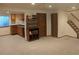 Open living room featuring carpet flooring, built-in shelving, and access to a staircase and partial kitchen area at 21734 Farmingdale Ct, Parker, CO 80138