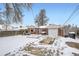 Backyard view of garage, patio, and snowy landscape at 7505 Robinson Way, Arvada, CO 80003