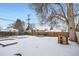 Snowy backyard with playset, garden beds and wooden fence at 7505 Robinson Way, Arvada, CO 80003