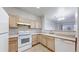 Functional kitchen with white appliances, light wood cabinets, and vinyl flooring at 12327 E Tennessee Dr # 107, Aurora, CO 80012