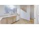 Clean kitchen with white dishwasher, bright sink, light wood cabinets, and a view into the living area at 12327 E Tennessee Dr # 107, Aurora, CO 80012