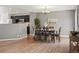 A dining room is displayed with wood flooring, a dining room table, a light fixture and an open concept to the kitchen at 11082 Fillmore Way, Northglenn, CO 80233