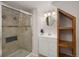 Bathroom features a glass door shower, white sink vanity, and open shelving unit, maximizing space at 6073 W Adriatic Pl, Lakewood, CO 80227