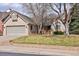 Brick home with a well-manicured lawn, mature trees, two car garage and a cozy front porch at 6073 W Adriatic Pl, Lakewood, CO 80227