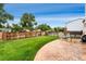 Landscaped backyard featuring a spacious grass area, stone patio with dining set, and a wooden privacy fence at 7796 Xavier Ct, Westminster, CO 80030