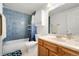 Well-lit bathroom with blue-tiled shower/tub combination, a marble vanity, and matching wall decor at 7796 Xavier Ct, Westminster, CO 80030
