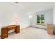 Bright, minimalist bedroom with neutral carpet, a vintage desk, and a large window offering natural light at 7796 Xavier Ct, Westminster, CO 80030