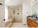 Well-lit bathroom featuring a glass shower and tub combination with tile surround and a wood vanity with double sinks at 301 Fairfax St, Denver, CO 80220
