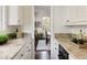 Galley kitchen with white cabinets, granite counters, and an opening that looks out to the dining area at 301 Fairfax St, Denver, CO 80220