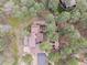 Aerial view of a secluded home featuring a fenced yard, mature trees, deck, patio, and circular driveway at 4515 Red Rock Dr, Larkspur, CO 80118