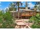 View of backyard landscaping with stone walkway leading to a wooden deck, blending with the natural surroundings at 4515 Red Rock Dr, Larkspur, CO 80118