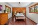 Charming bedroom with wood-paneled accent wall, hardwood floors, and natural light from large windows at 4515 Red Rock Dr, Larkspur, CO 80118