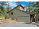 Image focuses on a two-car garage and green exterior, complemented by tasteful landscaping at 4515 Red Rock Dr, Larkspur, CO 80118
