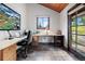 Bright home office featuring a built-in desk, natural light, and an adjacent outdoor view with vaulted wood ceilings at 4515 Red Rock Dr, Larkspur, CO 80118