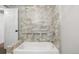Bright bathroom with a soaking tub surrounded by elegant gray tile, featuring built-in shower shelves at 3233 Meade St, Denver, CO 80211