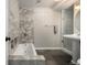 Bathroom featuring tiled tub, glass shower, and pedestal sink illuminated by modern lighting at 3233 Meade St, Denver, CO 80211