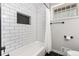 Bathroom featuring white tiled shower, modern matte fixtures, glass block window, and built in shower niche at 6538 S Lee Ct, Centennial, CO 80121