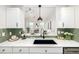 Kitchen features a farmhouse sink, white cabinets and green tile backsplash at 475 W 12Th Ave # 6B, Denver, CO 80204