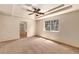 Spacious main bedroom with a tray ceiling, large window, neutral carpet, and an en-suite bathroom at 21444 E Lehigh Ave, Aurora, CO 80013