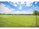 Lush green open field under a bright blue sky with fluffy white clouds in a well-maintained community at 21444 E Lehigh Ave, Aurora, CO 80013