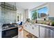 Sunlit kitchen showcasing white cabinets, a stainless steel stove, and modern backsplash tiles at 3346 W 33Rd Ave, Denver, CO 80211
