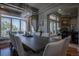 Elegant dining room with a long wooden table, modern chandelier, and large windows offering scenic views at 10515 Lucas Ave, Franktown, CO 80116