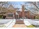 Beautiful brick home with manicured lawn and inviting entryway, framed by mature trees and winter's touch at 2020 E 4Th Ave, Denver, CO 80206