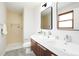 Bright bathroom with double sinks, wood vanity, modern fixtures, and a step-in shower with tan tiling at 4682 Chatham St, Boulder, CO 80301