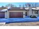 Exterior of charming townhome with brown garage door and snow-covered driveway at 1120 Cholla Ln, Broomfield, CO 80020