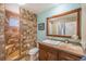 Bathroom featuring a shower with eye-catching tilework, a modern sink, and a decorative wood-framed mirror at 8893 W Ontario Ave, Littleton, CO 80128