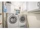 Bright laundry room featuring white washer and dryer, storage cabinets, and a mountain-themed art piece at 8893 W Ontario Ave, Littleton, CO 80128