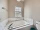 Relaxing soaking tub surrounded by marble-look tile in a neutral-toned bathroom at 9363 Amison Cir # 106, Parker, CO 80134