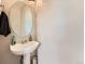 A sleek half bathroom showcasing a pedestal sink, round mirror, and neutral decor at 9363 Amison Cir # 106, Parker, CO 80134