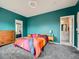 Bright main bedroom boasts turquoise walls, grey carpet, colorful bedding, and an en-suite bathroom at 9363 Amison Cir # 106, Parker, CO 80134