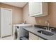 Well-lit laundry room with modern washer and dryer, countertop, and storage cabinet at 16302 Parkside Dr, Parker, CO 80134