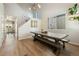 Bright dining room featuring a long wooden table with bench seating, modern light fixture, and wood floors at 4947 Stoneham Ave, Castle Rock, CO 80104