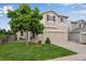 Inviting two-story home featuring a green lawn, mature tree, and a two car garage at 1179 S Alton Ct, Denver, CO 80247