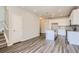Open-concept living space flows into kitchen; features stylish wood-look floors and staircase at 6827 Huddersfield Ln, Castle Pines, CO 80108