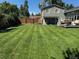A fully-fenced backyard with an expansive lawn, mature trees, and a deck for outdoor dining and entertaining at 8700 S Ammons St, Littleton, CO 80128